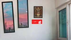 Un couloir orné de tableaux encadrés, un panneau rouge avec une inscription blanche et une porte en verre.