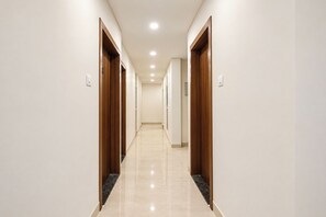 A corridor with wooden doors and a tiled floor. - Via Galaxy Hospitality (Pune)