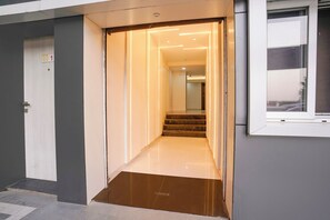 A hallway with a door marked '1' leading to a staircase. - Via Galaxy Hospitality (Pune)