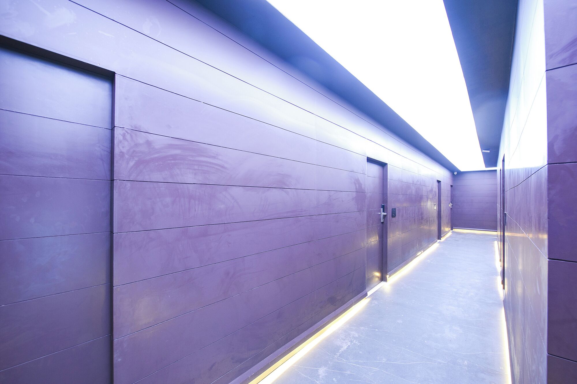 Un couloir au design moderne, avec une série de portes et un sol réfléchissant.