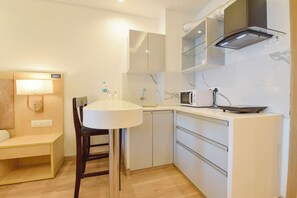 A compact kitchen with a microwave, a small sink, and a chair. - Fabhotel The Grand Anukampa With Swimming Pool (Jaipur)
