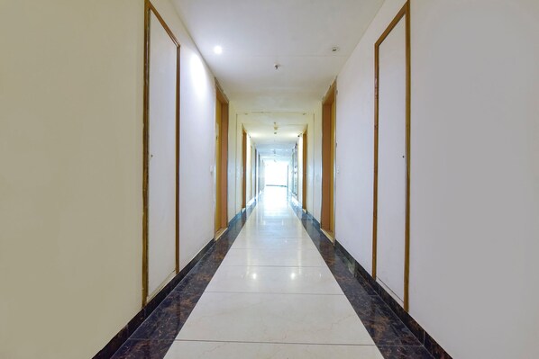 A long, narrow hallway with a tiled floor and doors on both sides.