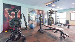 Un gimnasio con equipo de levantamiento de pesas, pelotas de ejercicio y bancos.