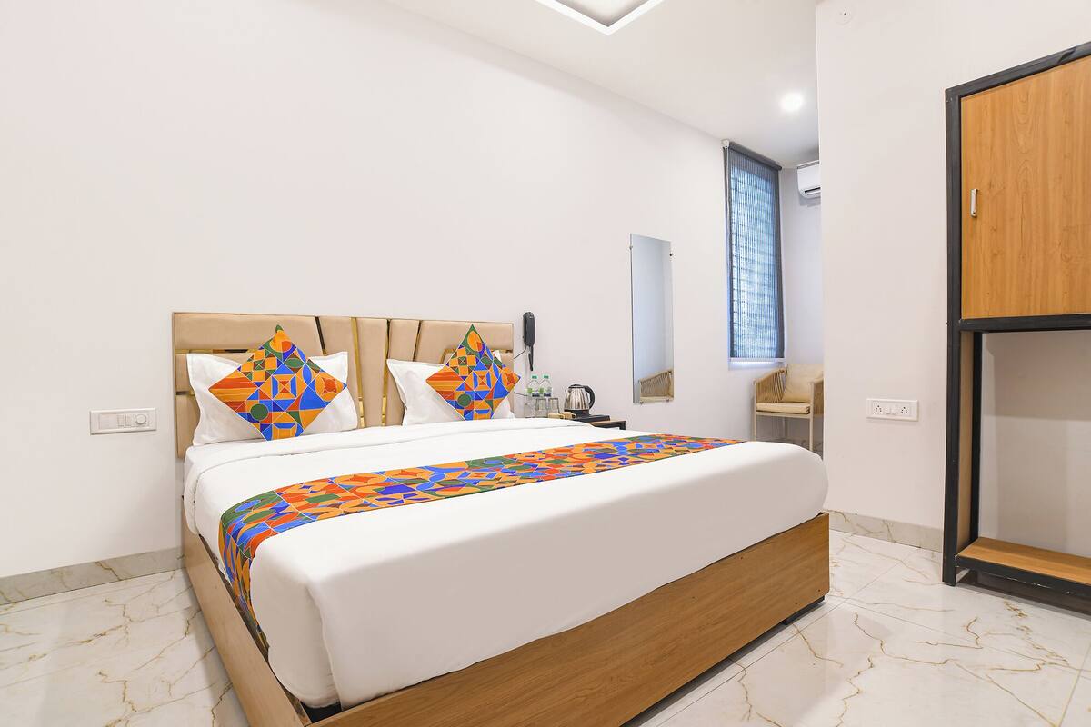 Una habitación de hotel moderna con una cama, una mesita de noche, un espejo y un armario.