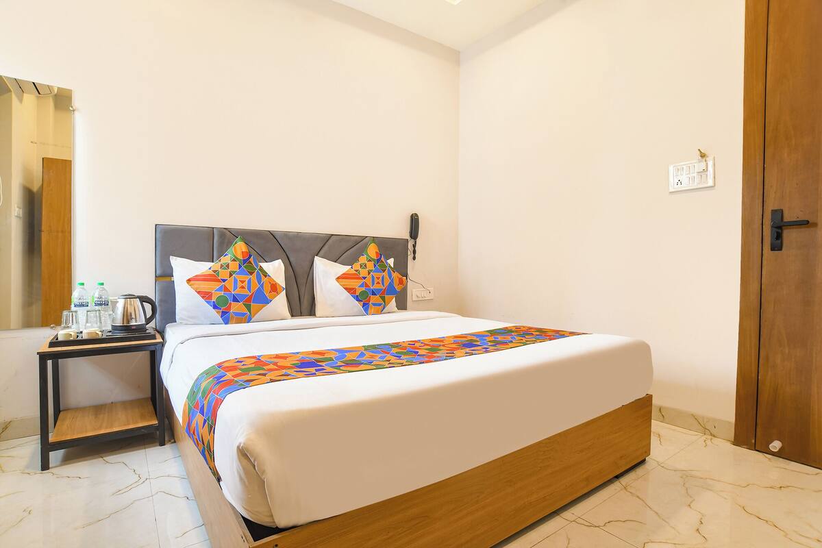 Una habitación de hotel con una cama, una mesita de noche, un teléfono y una puerta.