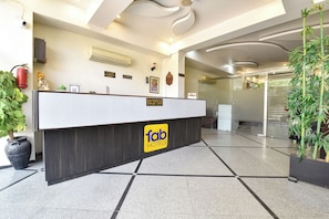 A hotel reception desk with a reception sign, a fire extinguisher, and a security camera. - FabHotel Harsh Paradise - Malviya Nagar (Jaipur)