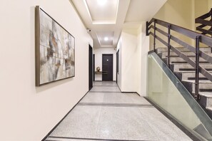 A hallway with a staircase, a framed abstract painting, and a door at the end. - FabHotel Harsh Paradise - Malviya Nagar (Jaipur)