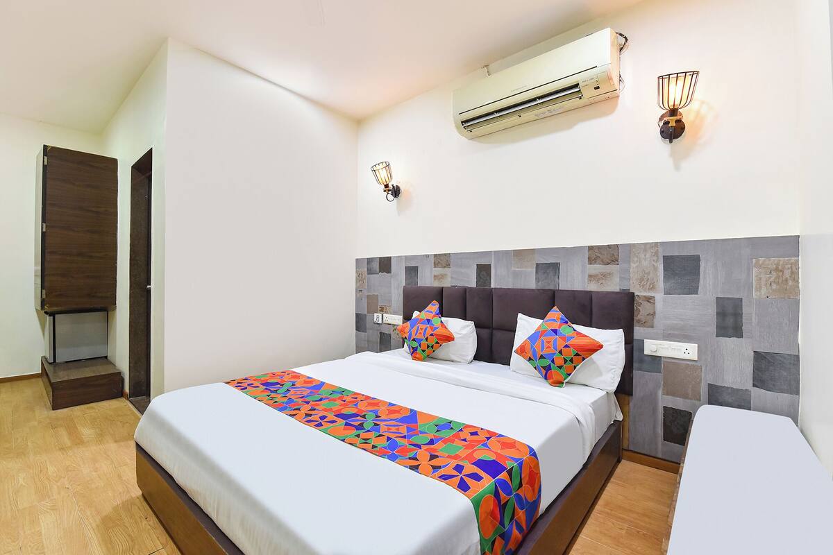 Ein Hotelzimmer mit Bett, Nachttisch, Klimaanlage und Wandleuchte.