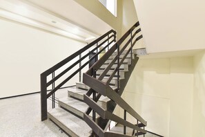 A staircase with a metal railing, concrete steps, and a plain wall. - FabHotel Harsh Paradise - Malviya Nagar (Jaipur)