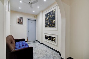 Un pasillo con una puerta marcada '201', un cuadro enmarcado en la pared y un ventilador de techo.