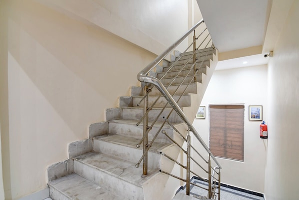 A staircase with metal handrails and a fire extinguisher on the wall. - FabHotel Airport View - Nr. Kolkata Airport (Alipur)