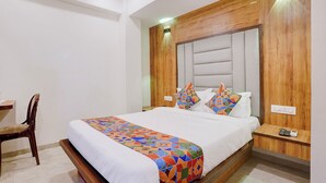 Ein Hotelzimmer mit Bett, Stuhl, Nachttisch und Holz-Kopfteil.