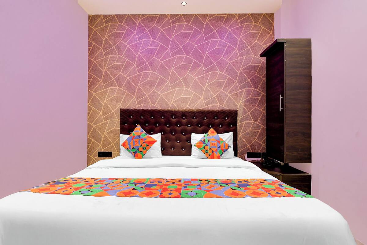 A bed with a geometric-patterned bedspread, a tufted headboard, and two decorative pillows.