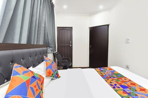 Hotellihuone, jossa on sänky, tuoli, työpöytä ja vaatekaappi.