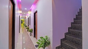 Un pasillo de hotel con suelo de mármol, plantas en macetas y una escalera.