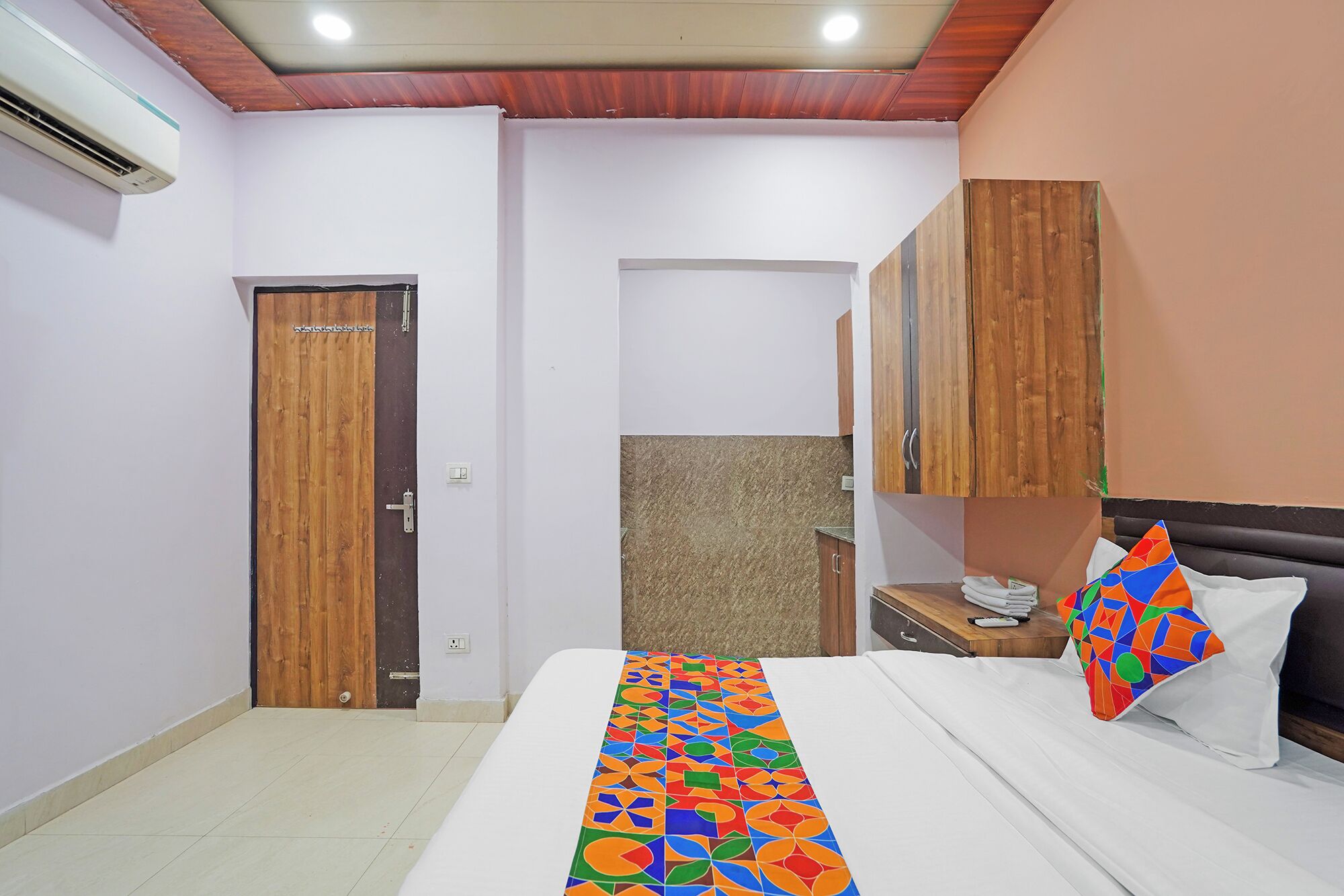 Una habitación de hotel con cama, puerta de madera, baño con ducha y techo de madera.