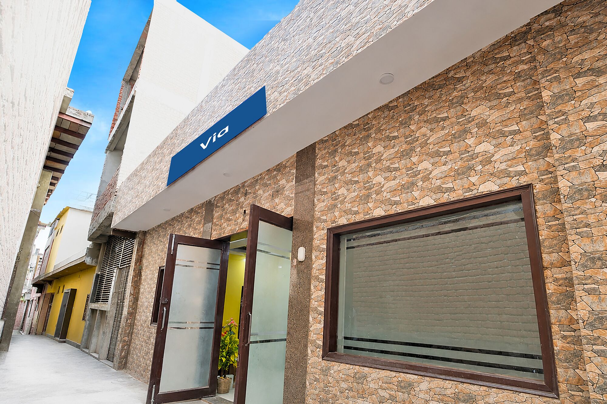 A building with a stone facade, a blue sign with 'Vigo' on it, and a closed shutter on the right.