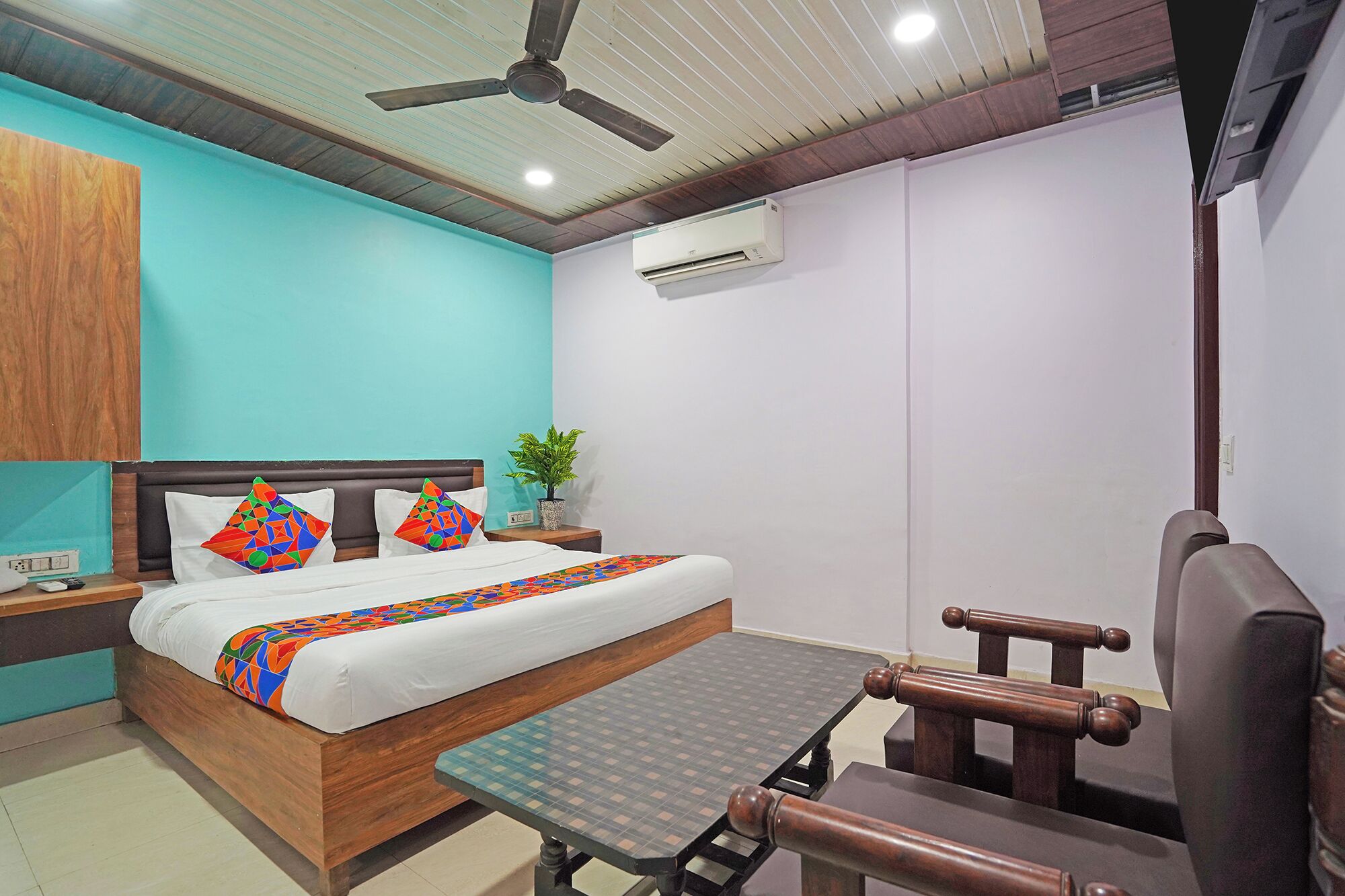 A bedroom with a bed, a desk, a chair, a ceiling fan, and an air conditioning unit.