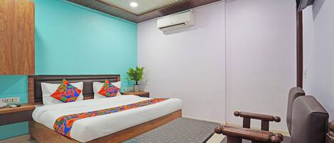 A bedroom with a bed, a desk, a chair, a ceiling fan, and an air conditioning unit.