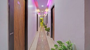 Un pasillo con puertas, plantas en macetas y piso de baldosas.