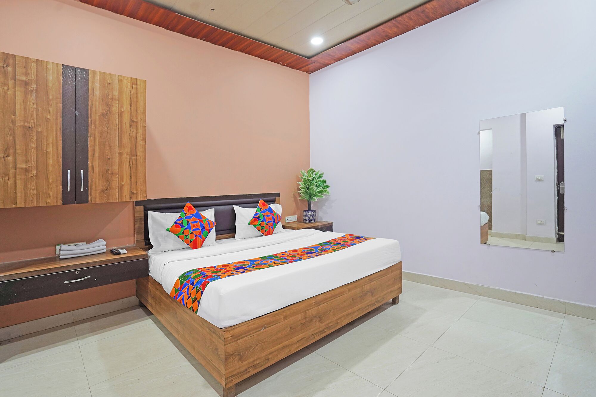 A bedroom with a wooden bed, a nightstand, a mirror, and a wardrobe.