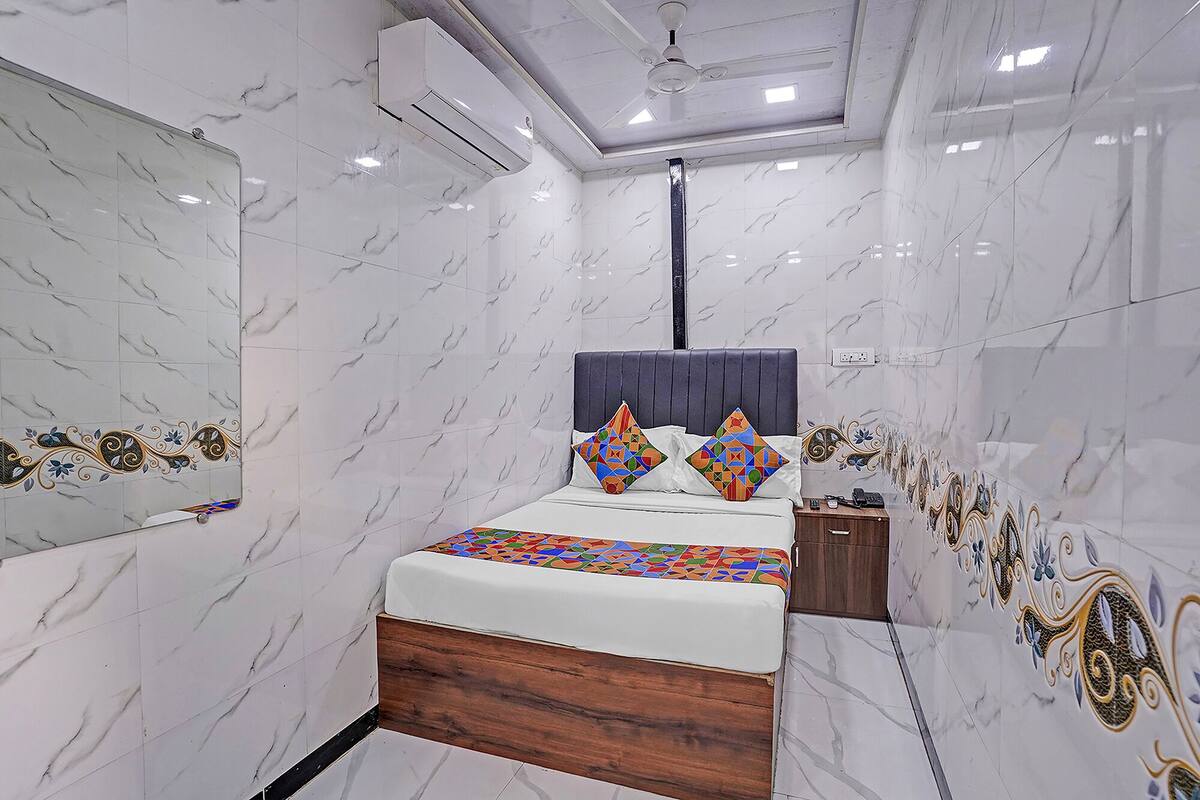 A bedroom with a bed, a nightstand, a mirror, and a ceiling fan.