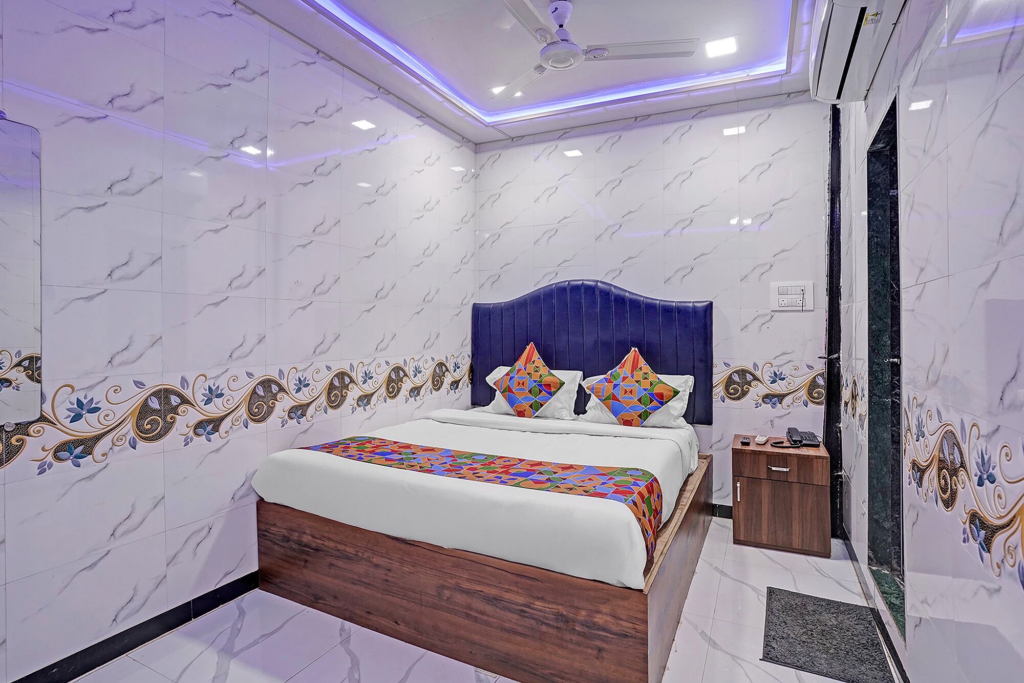 A bedroom with a bed, a ceiling fan, a nightstand, and a small wooden cabinet.