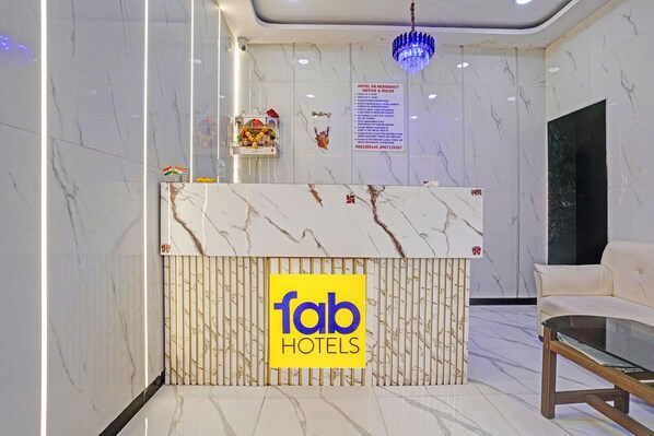 A hotel reception desk with a marble top and a sign reading 'fab hotels'. - Via Sr Residency (Mumbai)