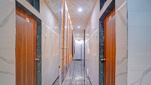 A corridor with marble walls and wooden doors, leading to a hallway. - Via Sr Residency (Mumbai)