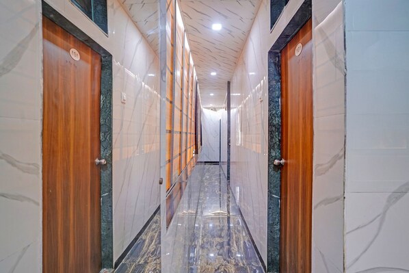 Un pasillo con paredes de mármol y puertas de madera, que conduce a un distribuidor.