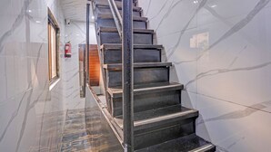 Eine Marmortreppe mit Metallgeländern, die zu einer Holztür führt.