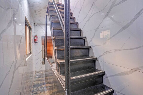 Una escalera de mármol con barandales de metal que conduce a una puerta de madera.