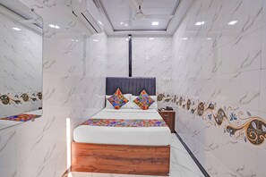A bedroom with a bed, a wooden headboard, a nightstand, and a wall with decorative tiles. - Via Sr Residency (Mumbai)