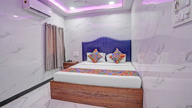 A hotel room with a bed, a headboard, a nightstand, and an air conditioning unit. - Via Sr Residency (Mumbai)