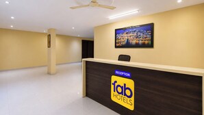 Ein Empfangsschalter mit einem Schild 'fab hotels', einem Deckenventilator und einem gerahmten Bild an der Wand.