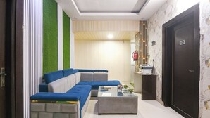 Un salon moderne avec un canapé d’angle, une table basse et un comptoir d’accueil.