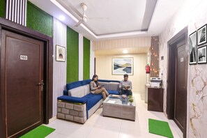En moderne lobby med en blå sofa, et receptionsskrivebord og en ventilator i loftet.