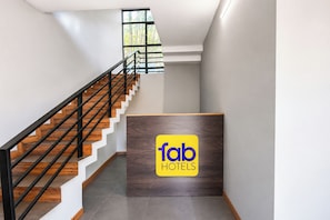 Interior modern d'un hotel amb una escala de fusta, una recepció i un gran finestral.