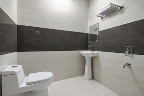 A modern bathroom with a toilet, pedestal sink, and a towel rack. - FabHotel Legend Stay - Dwarka Sector 7 (New Delhi)