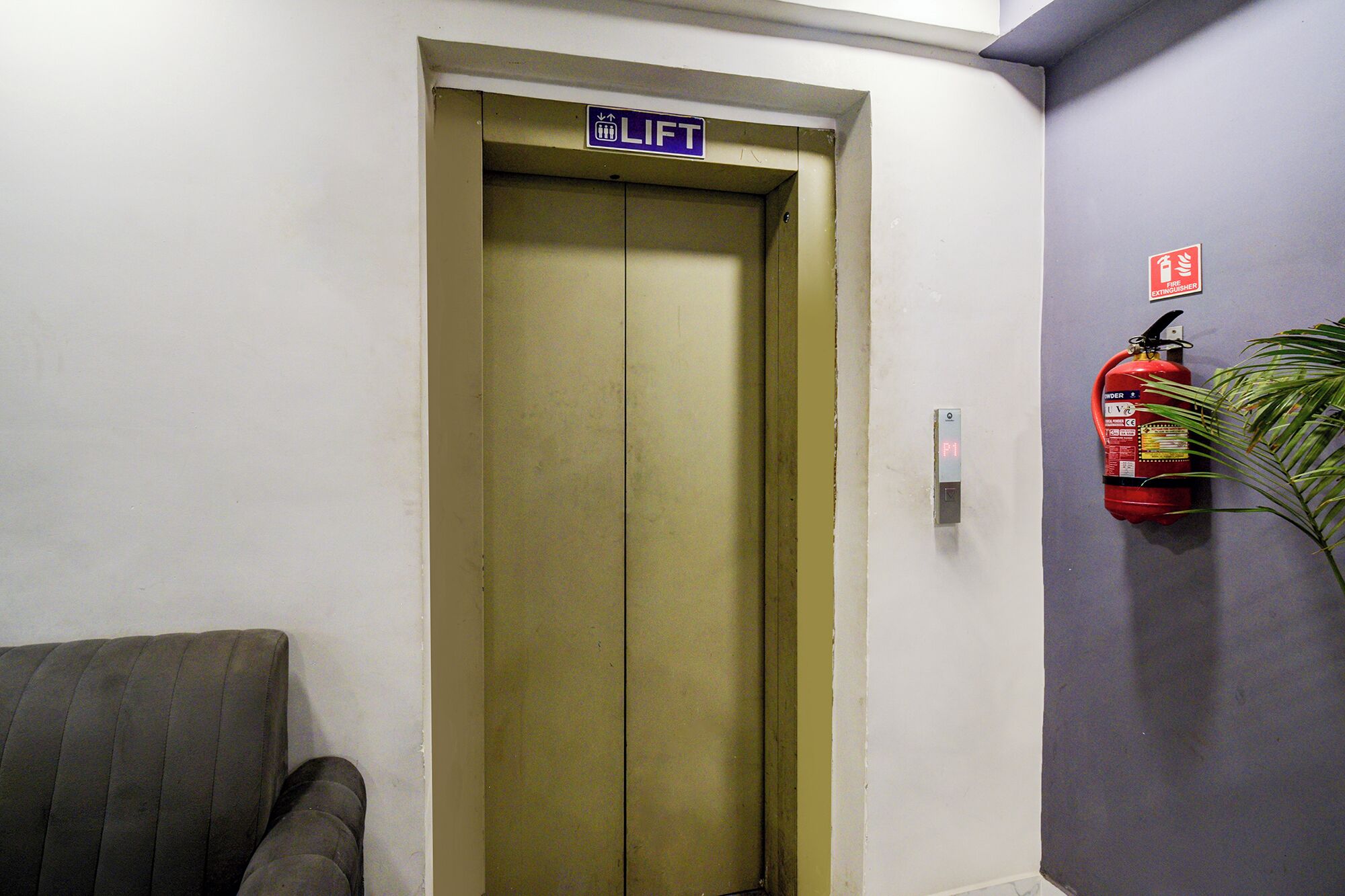 An elevator with a 'LIFT' sign, a fire extinguisher, and a chair.