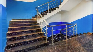 Una escalera con barandillas de metal, escalones de mármol y una pared azul y blanca.