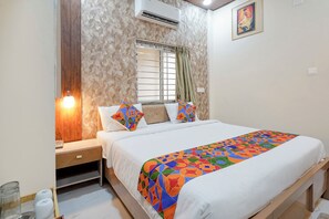 A bedroom with a bed, a nightstand, a window with curtains, an air conditioner, and a painting on the wall. - Fabhotel Grant Heights - Nr. Biju Patnaik International Airport (Bhubaneshwar)