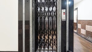 An elevator with a metal gate, a digital display, and a wall with a patterned design. - FabHotel Jaya Grand - Nr. Railway Station (Guntur)
