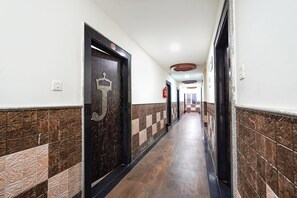 A hallway with tiled walls, a wooden floor, and doors with a crown symbol.