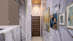 A hallway with marble walls, wooden door, and framed artwork. - Fabhotel Comfort Zone (Mumbai)