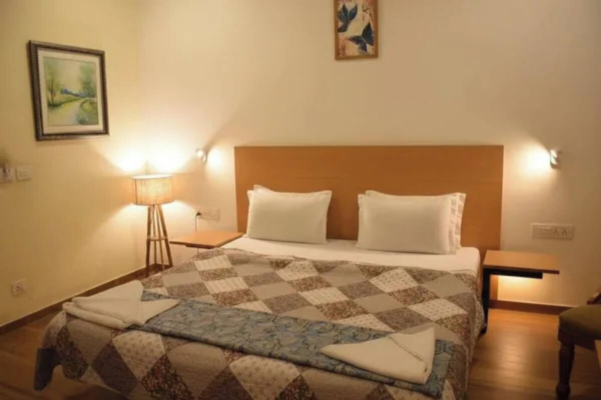 Ein Hotelzimmer mit einem großen Bett, zwei Nachttischen, einer Stehlampe und einem Gemälde an der Wand.
