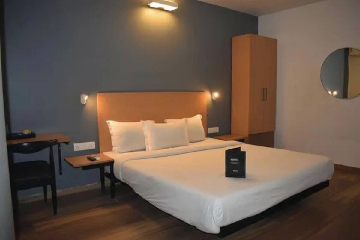 Ein Hotelzimmer mit einem Bett, einem Schreibtisch, einem Stuhl, einem Kleiderschrank und einem Spiegel.