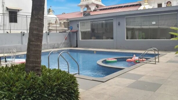 A swimming pool with a small hot tub, surrounded by a low wall and a palm tree. - FabHotel Prime Plaza Inn - 800M From Calangute Beach (Calangute)