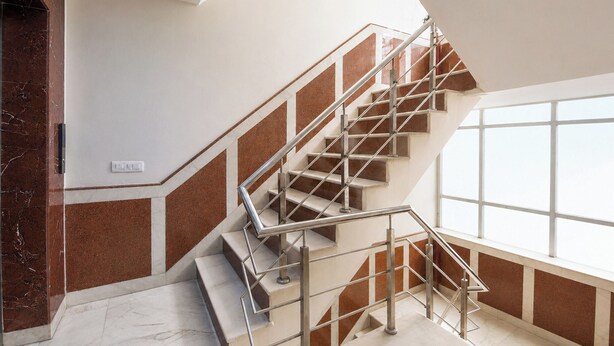 A staircase with a metal railing, marble walls, and a large window. - FabHotel Dev Palace II - Nr Ashok Vihar (New Delhi)