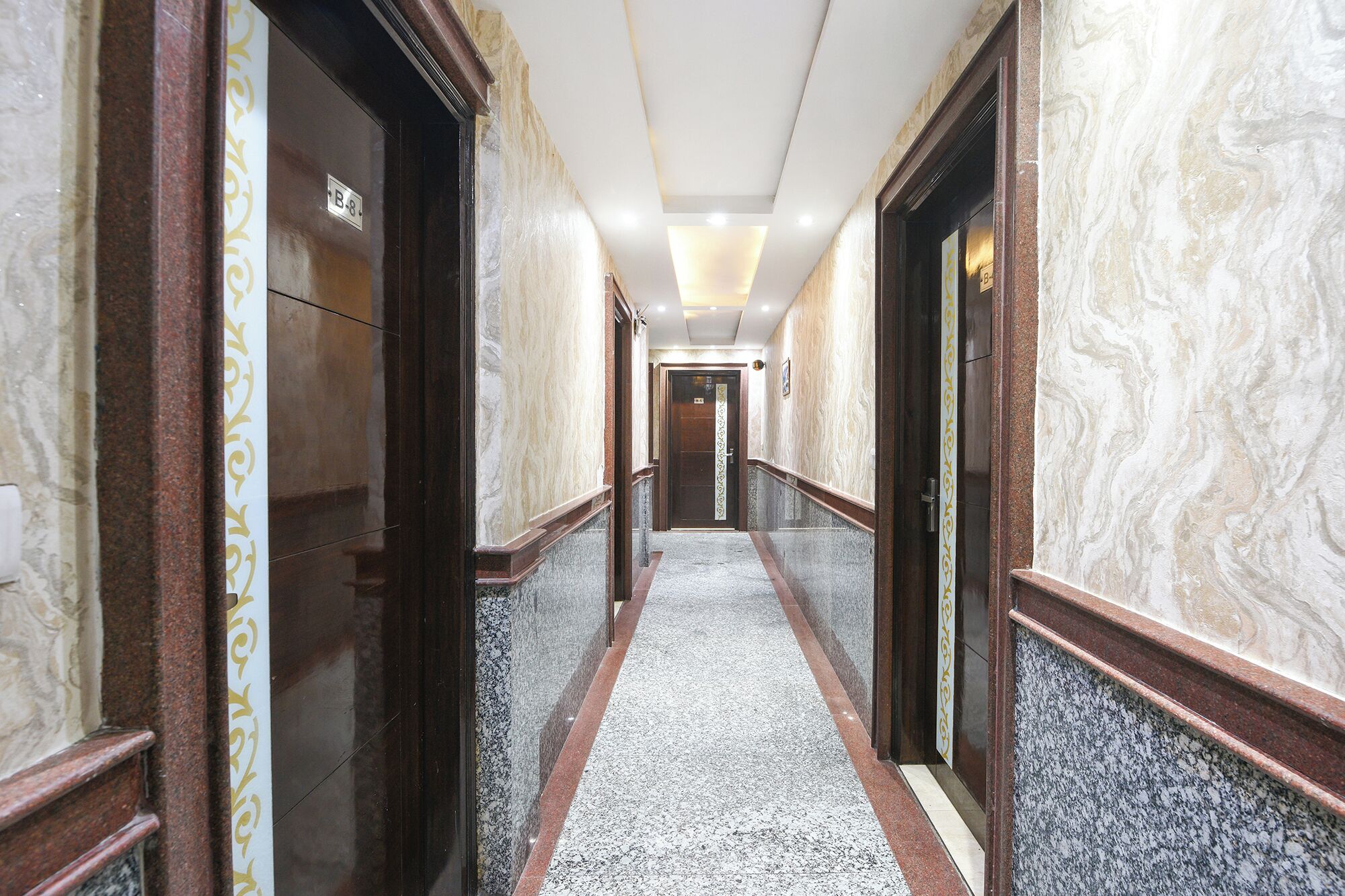 A marble-lined hallway with doors marked 'B-8' and a carpeted floor.